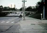 Street dips below mid-block pedestrian bridge.